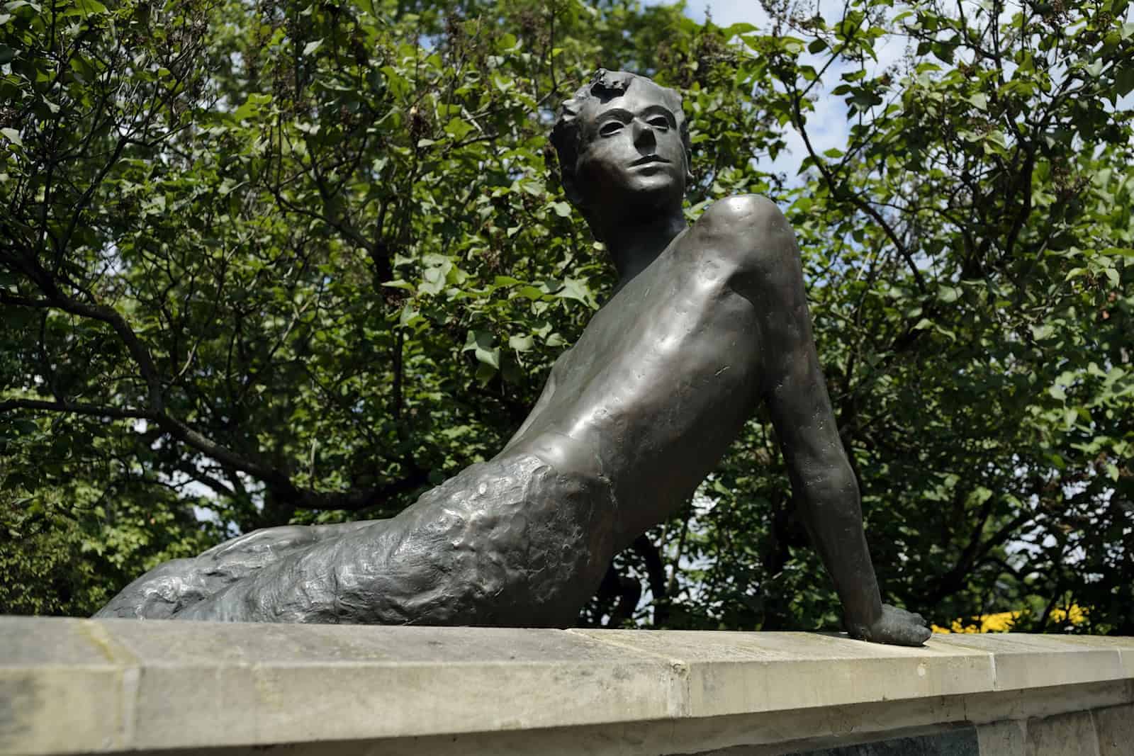 Bronzeplatik von Erich Kästner als kleiner Junge, auf einer Mauer sitzend