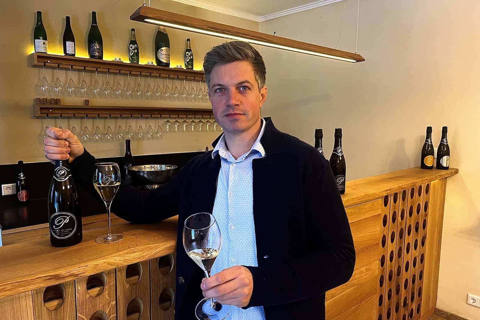 Winzer Hendrik Weber hält Sekt in der Hand.