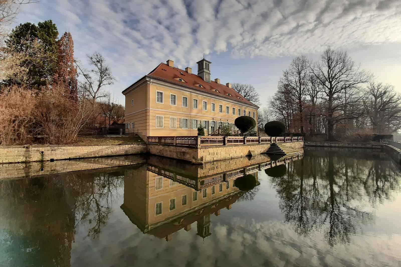 Das Jagdschloss Graupa spiegelt sich im See.