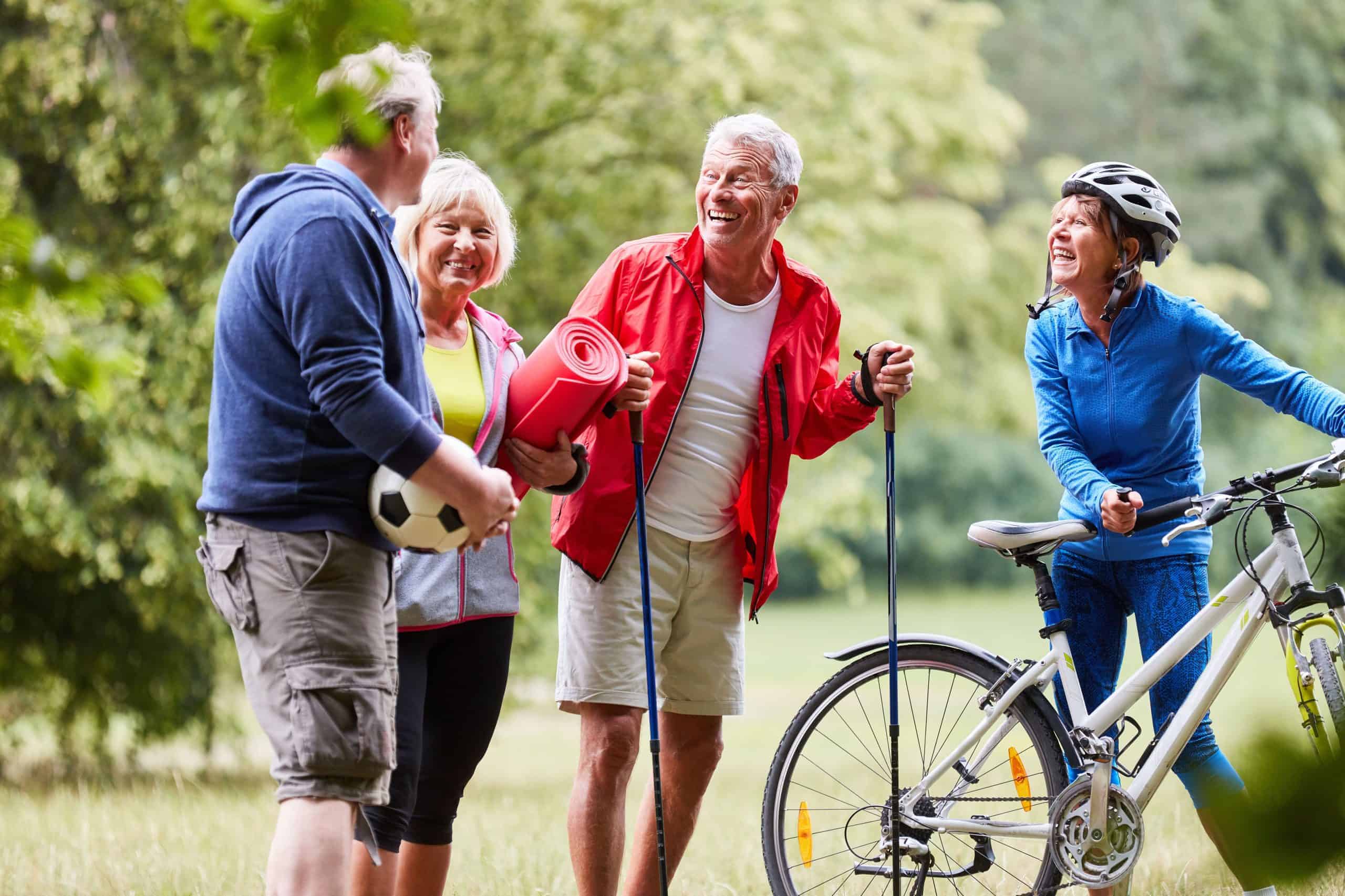 Ältere Menschen stehen beim Ausüben verschiedener Sportarten in der Natur zusammen.
