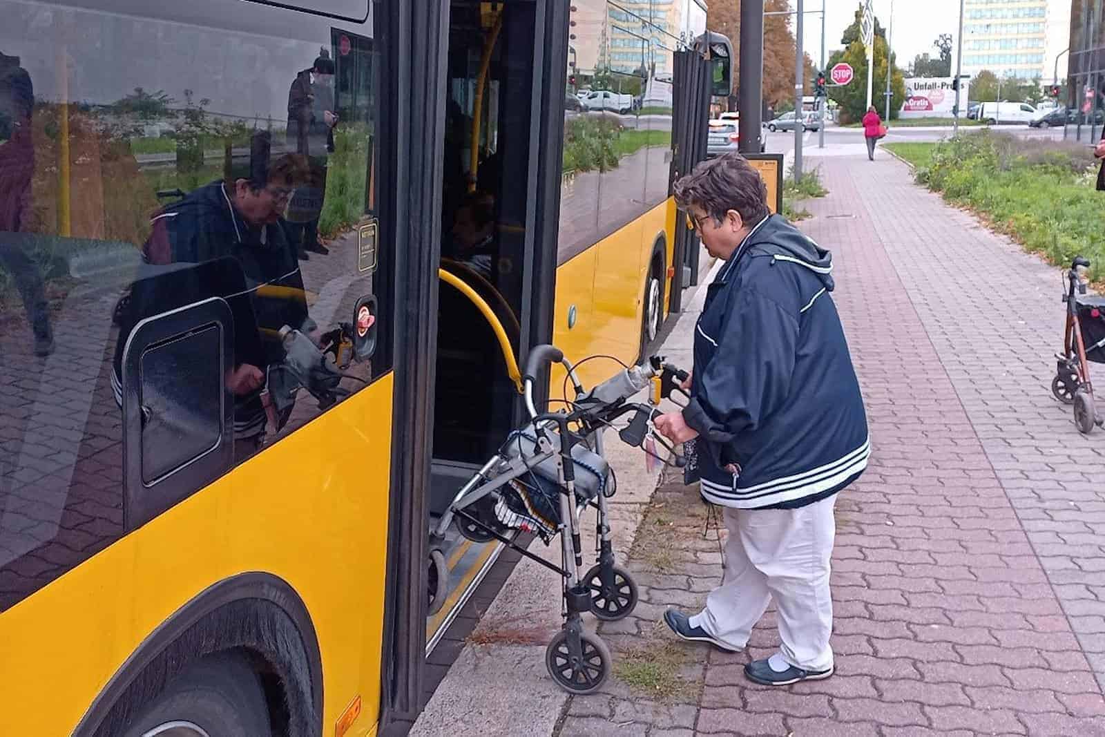Frau steigt mit Rollator in Bus