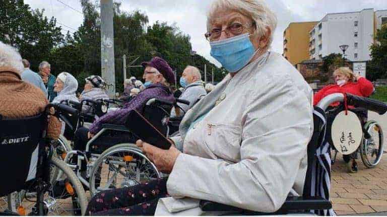 Roemarie John sitzt mit Hygienemaske im Rollstuhl, um die Stadtbesichtigung zu genießen. Sie nutzt die Zeit für Ihr Smartphone.