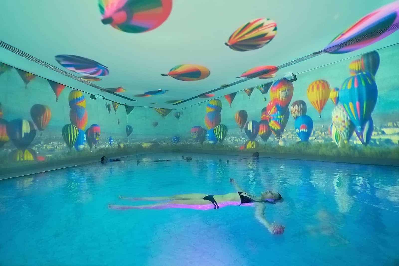 Eine Dame im Bikini liegt auf der Oberfläche des Solethermebads Bad Elster und genießt das Ambiente.