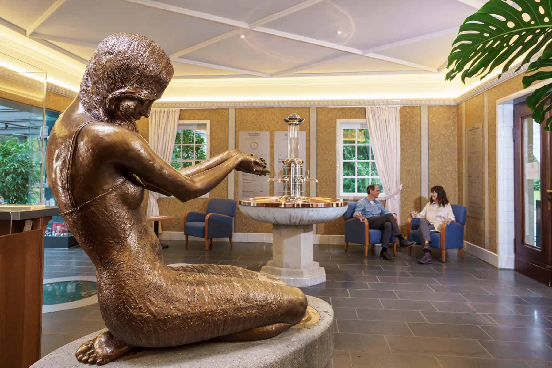 Im Vordergrund ist eine Statue namens Wettina zu sehen, die in der Wettinquelle in Bad Brambach die Radon-Mineralheilquelle darstellt.