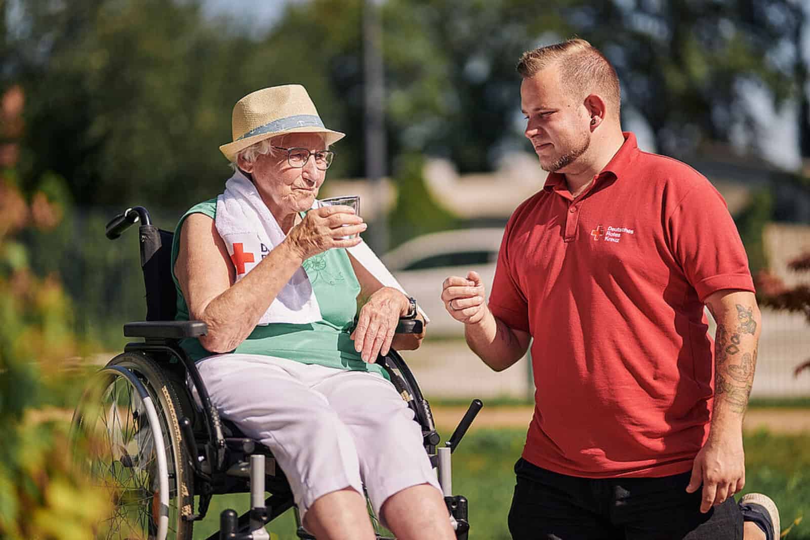Ein DRK-Mitarbeiter der Tagespflegeeinrichtung vom DRK-Kreisverband Fläming-Spreewald in Luckenwalde reicht einer Seniorin ein Glas Wasser. Foto: DRK