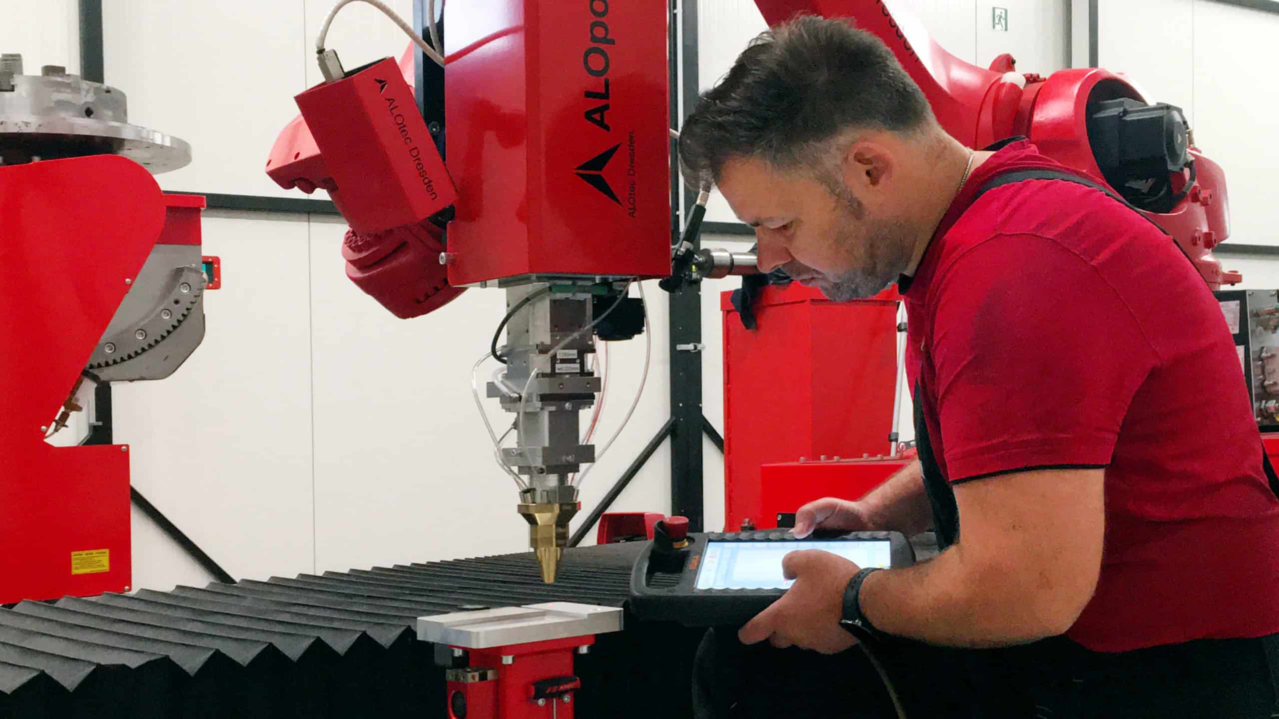 Ein Mitarbeiter der Firma ALOtec bei der Arbeit an einer Laseranlage.