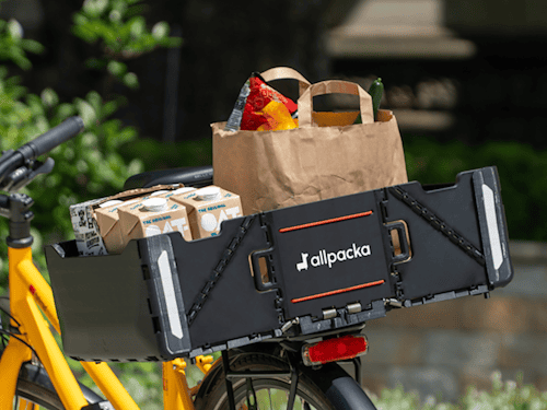 Die aufgeklappte Allpacka One auf dem Gepäckträger eines Fahrrads.