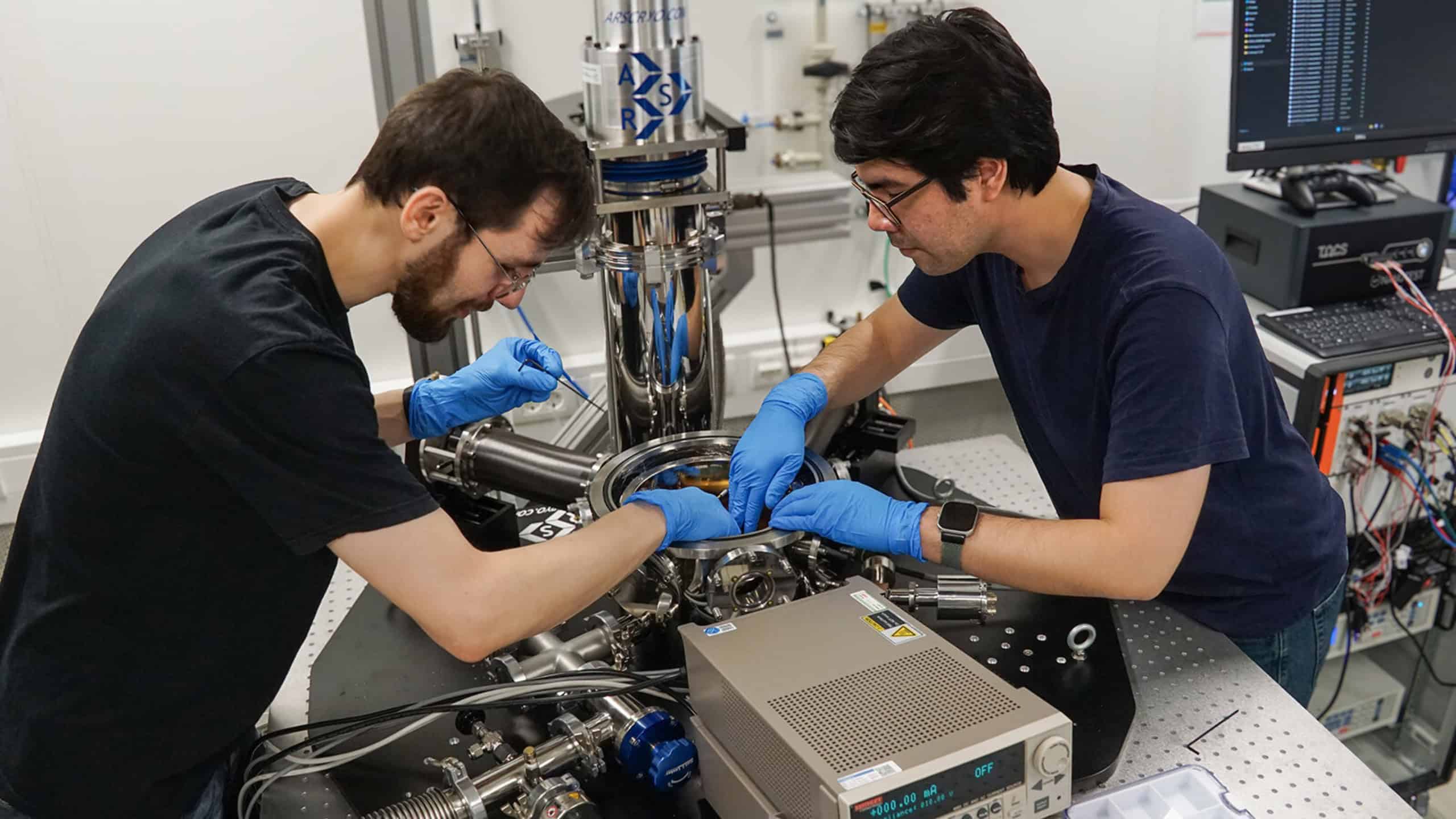 Zwei Wissenschaftler installieren einen Teststand in einem Helium-Kryostaten an der TU Chemnitz.