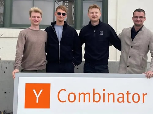 Vier Gründer des Dresdner Raketen-Startups RATLOG stehen vor einem Schild des Y Combinator.