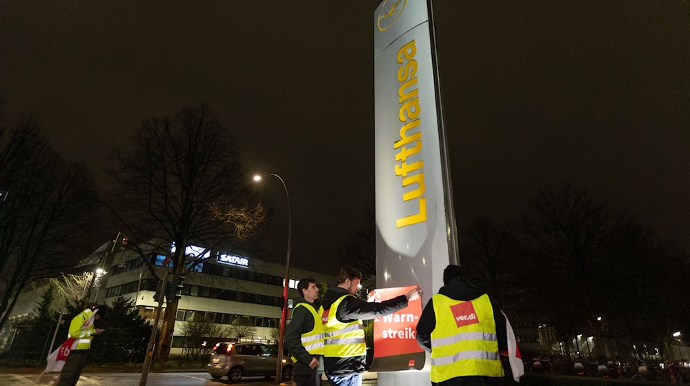 Streikende hängen Plakate mit der Aufschrift «Warnstreik!» bei der Lufthansa Technik auf. / Foto: Bodo Marks/dpa