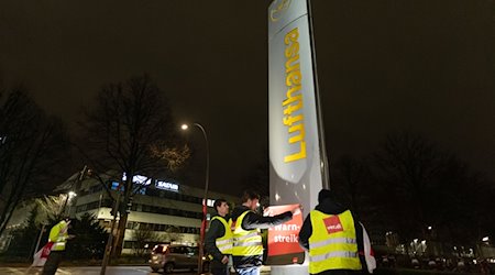 Streikende hängen Plakate mit der Aufschrift «Warnstreik!» bei der Lufthansa Technik auf. / Foto: Bodo Marks/dpa