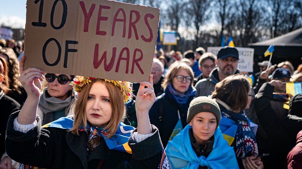 Eine Frau nimmt an der Solidaritätsdemonstration des Vereins Vitsche «Zusammen Demokratie verteidigen» mit einem Schild mit der Aufschrift «10 years of war» teil. / Foto: Fabian Sommer/dpa