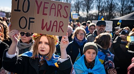 Eine Frau nimmt an der Solidaritätsdemonstration des Vereins Vitsche «Zusammen Demokratie verteidigen» mit einem Schild mit der Aufschrift «10 years of war» teil. / Foto: Fabian Sommer/dpa