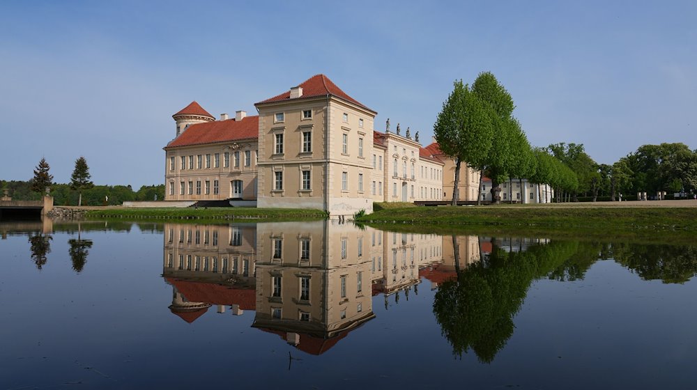 Die Parkseite von Schloss Rheinsberg mit dem Kurt Tucholsky Literaturmuseum spiegelt sich in dem vom Grienericksee gespeisten Wasser des Schlossgrabens. / Foto: Soeren Stache/dpa/Archivbild