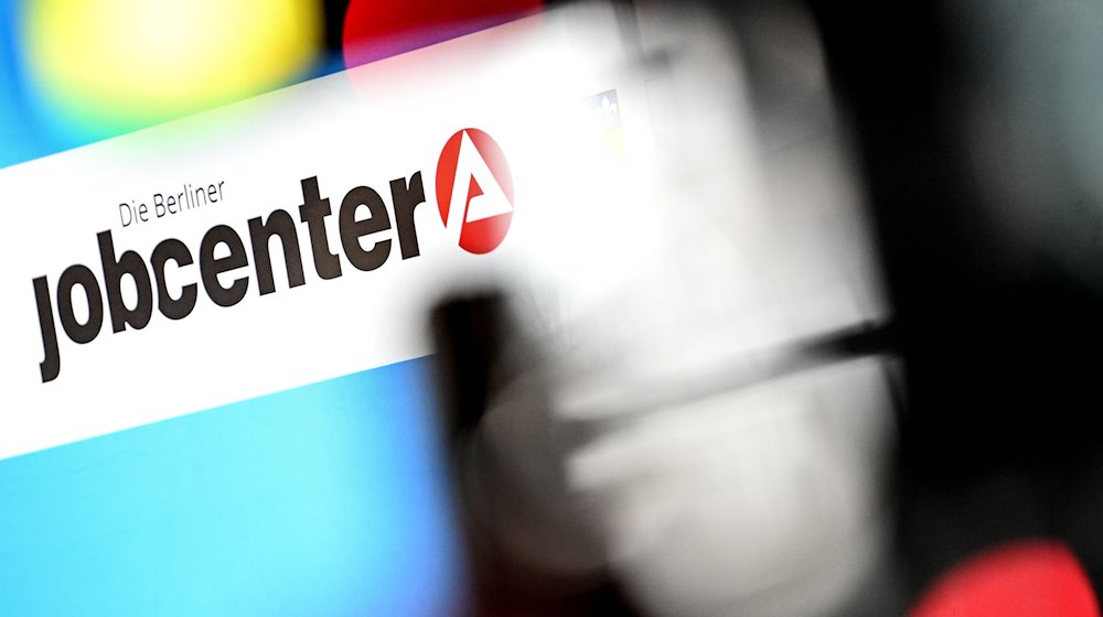 Das Logo des Jobcenters bei einer Pressekonferenz. / Foto: Britta Pedersen/dpa