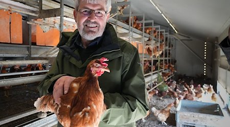 Axel Vogel (Bündnis 90/Die Grünen), Brandenburger Minister für Landwirtschaft, Umwelt und Klimaschutz, hält während des Besuchs der Wustermarker Bio-Ei GmbH ein Huhn im Arm. / Foto: Soeren Stache/dpa