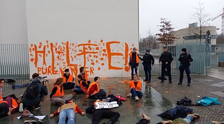 Aktivistinnen und Aktivisten der Letzten Generation sitzen vor einer Wand des Bundeskanzleramts. / Foto: Letzte Generation/dpa