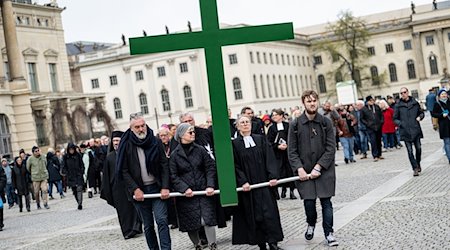 Gläubige tragen bei der Karfreitagsprozession der St. Marienkirche ein grünes Kreuz über den Bebelplatz. / Foto: Fabian Sommer/dpa