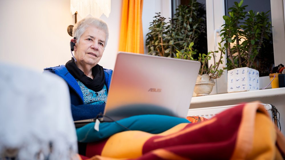 Elke Schilling, Gründerin von Silbernetz, telefoniert im Home­office auf ihrem Sofa sitzend von ihrer Berliner Wohnung aus. / Foto: Christoph Soeder/dpa