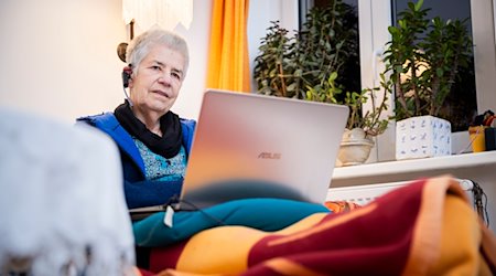 Elke Schilling, Gründerin von Silbernetz, telefoniert im Home­office auf ihrem Sofa sitzend von ihrer Berliner Wohnung aus. / Foto: Christoph Soeder/dpa