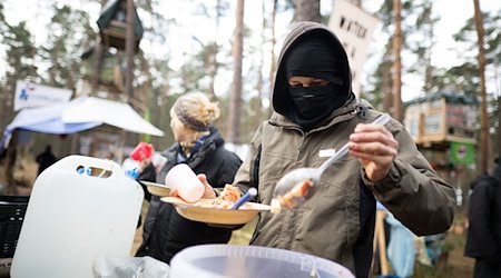 Ein Aktivist nimmt sich in einem Protestcamp nahe der Tesla-Gigafactory eine Portion Porridge. / Foto: Sebastian Christoph Gollnow/dpa