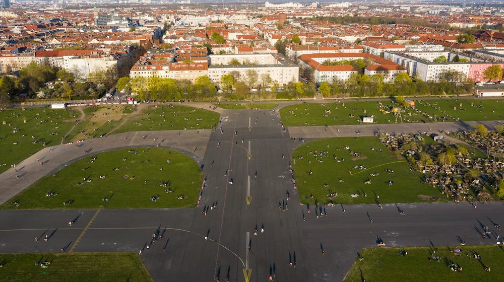 Zahlreiche Menschen sind während des Sonnenuntergangs auf dem Tempelhofer Feld unterwegs - im Hintergrund ist der Bezirk Neukölln zu sehen. / Foto: Christophe Gateau/dpa/Archivbild