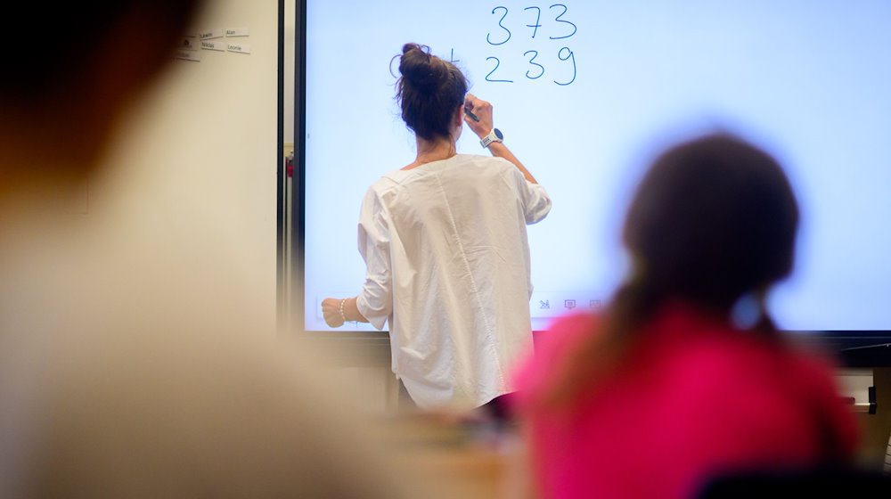 Ein Lehrerin schreibt auf eine digitale Schultafel im Klassenraum. / Foto: Julian Stratenschulte/dpa/Symbolbild