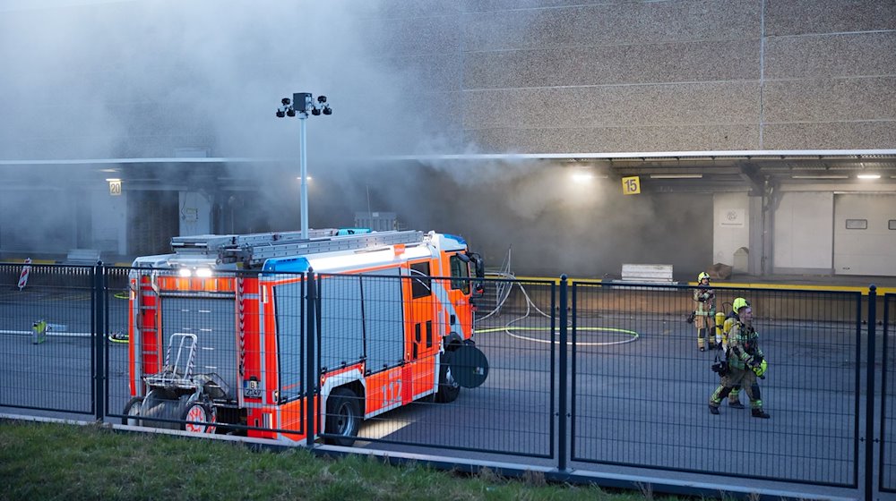 Feuerwehrkräfte sind dabei ein Feuer in einer Lagerhalle zu löschen. / Foto: Jörg Carstensen/dpa
