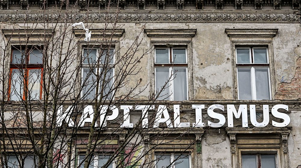 Das Wort „Kapitalismus“ ist an der Fassade eines Wohnhauses in der Kastanienallee in Prenzlauer Berg angebracht. / Foto: Jens Kalaene/dpa/Archivbild