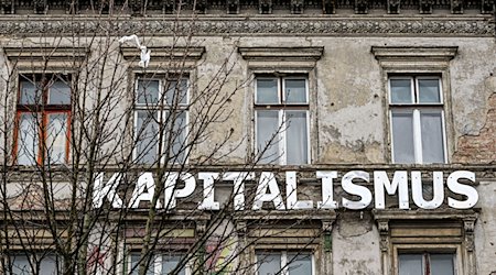 Das Wort „Kapitalismus“ ist an der Fassade eines Wohnhauses in der Kastanienallee in Prenzlauer Berg angebracht. / Foto: Jens Kalaene/dpa/Archivbild