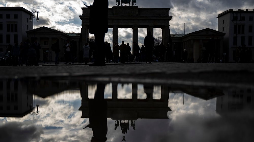 Das Brandenburger Tor spiegelt sich nach dem Regen in einer Pfütze. / Foto: Monika Skolimowska/dpa