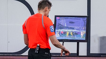 Schiedsrichter Daniel Siebert überprüft das Handspiel per Videobeweis. / Foto: David Inderlied/dpa