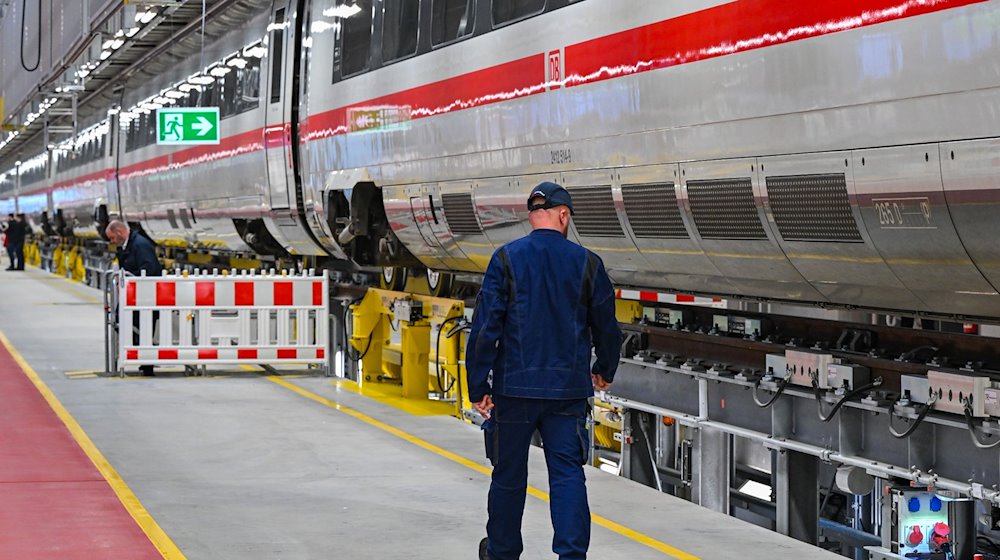 Ein Mitarbeiter der Deutschen Bahn geht an einem ICE des DB-Instandhaltungswerks vorbei. / Foto: Patrick Pleul/dpa/Archivbild