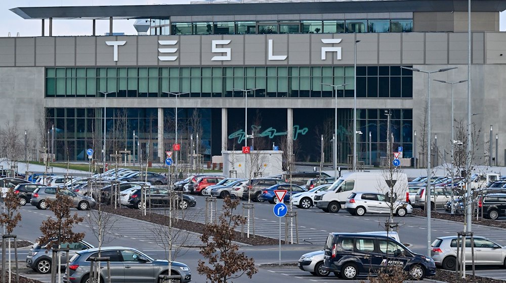 Autos von Mitarbeitern der Tesla-Fabrik stehen vor dem Werk. / Foto: Patrick Pleul/dpa