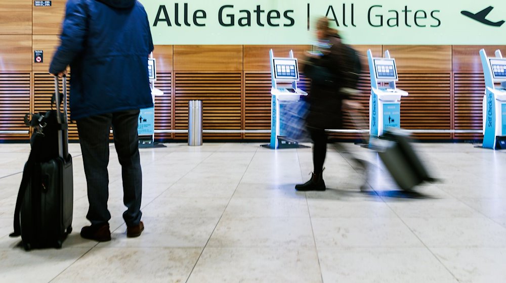 Fluggäste ziehen Rollkoffer durch die Halle von Terminal 1 des Flughafens BER. / Foto: Carsten Koall/dpa