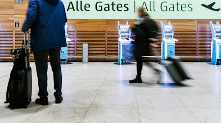 Fluggäste ziehen Rollkoffer durch die Halle von Terminal 1 des Flughafens BER. / Foto: Carsten Koall/dpa