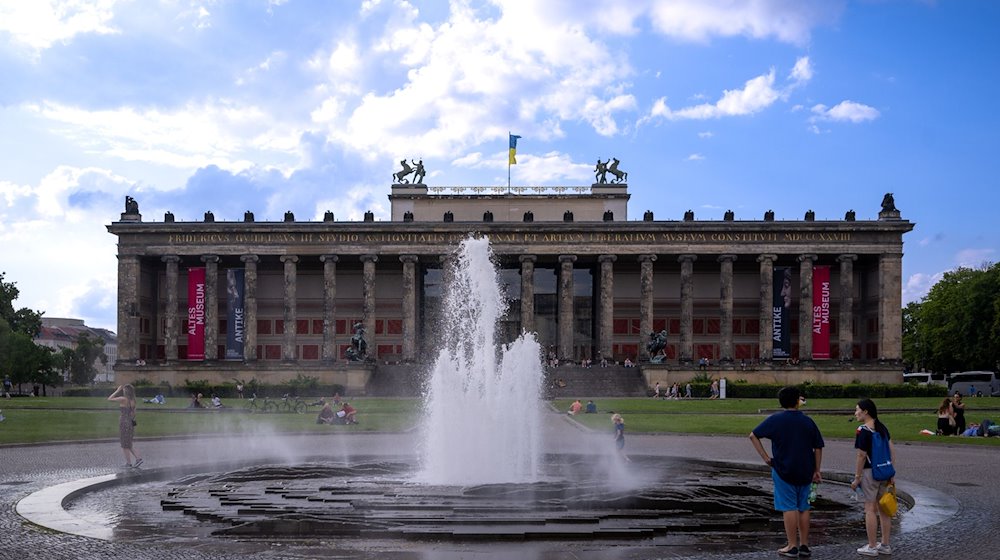 Touristen stehen vor einem Springbrunnen im Lustgarten vor der Kulisse des Alten Museums. / Foto: Monika Skolimowska/dpa/Archivbild