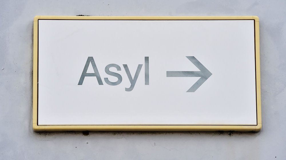 Ein Schild mit der Aufschrift «Asyl» hängt in Erstaufnahme für Asylbewerber  an einer Wand. / Foto: Uli Deck/dpa