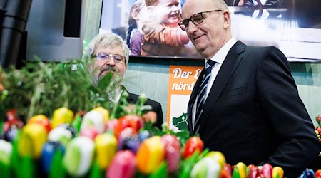 Dietmar Woidke (r,SPD), Ministerpräsident von Brandenburg, und Axel Vogel (Bündnis 90/Die Grünen), Landwirtschaftsminister, stehen hinter Kunstblumen. / Foto: Carsten Koall/dpa