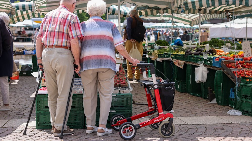 Zwei Senioren stehen mit Gehhilfen und Rollator auf dem Wochenmarkt in der Leipziger Innenstadt. / Foto: Jan Woitas/dpa