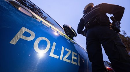 Eine Polizistin steht neben einem Polizeifahrzeug. / Foto: Marijan Murat/dpa