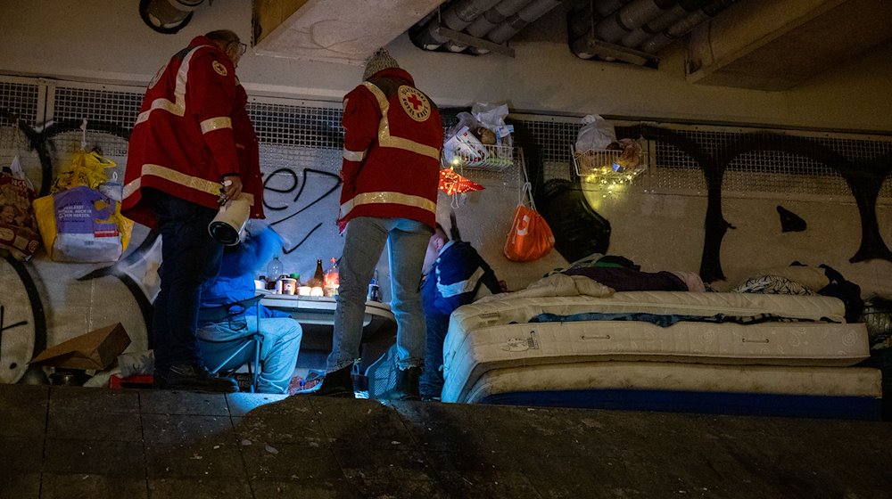 Helfer sind mit den Wärmebus vom Deutschen Roten Kreuz unterwegs und sprechen mit zwei Obdachlosen. / Foto: Christophe Gateau/dpa/Archivbild