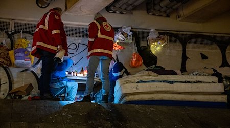 Helfer sind mit den Wärmebus vom Deutschen Roten Kreuz unterwegs und sprechen mit zwei Obdachlosen. / Foto: Christophe Gateau/dpa/Archivbild