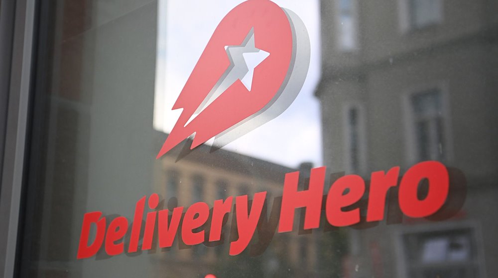 Logo und Schriftzug des Essenslieferdienstes Delivery Hero ist an einer Glasscheibe der Zentrale angebracht. / Foto: Britta Pedersen/dpa-Zentralbild/dpa