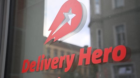 Logo und Schriftzug des Essenslieferdienstes Delivery Hero ist an einer Glasscheibe der Zentrale angebracht. / Foto: Britta Pedersen/dpa-Zentralbild/dpa