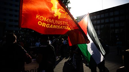 Die Flaggen der palästinensischen Autonomiegebiete sowie der kommunistischen Organisation sind bei einer Demo linker Gruppen zu sehen. / Foto: Christoph Soeder/dpa