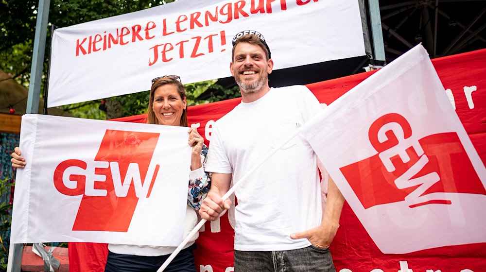 Sven und Bianca, beide Lehrer an einer Neuköllner Schule, stehen mit zwei GEW-Flaggen beim Warnstreik. / Foto: Fabian Sommer/dpa