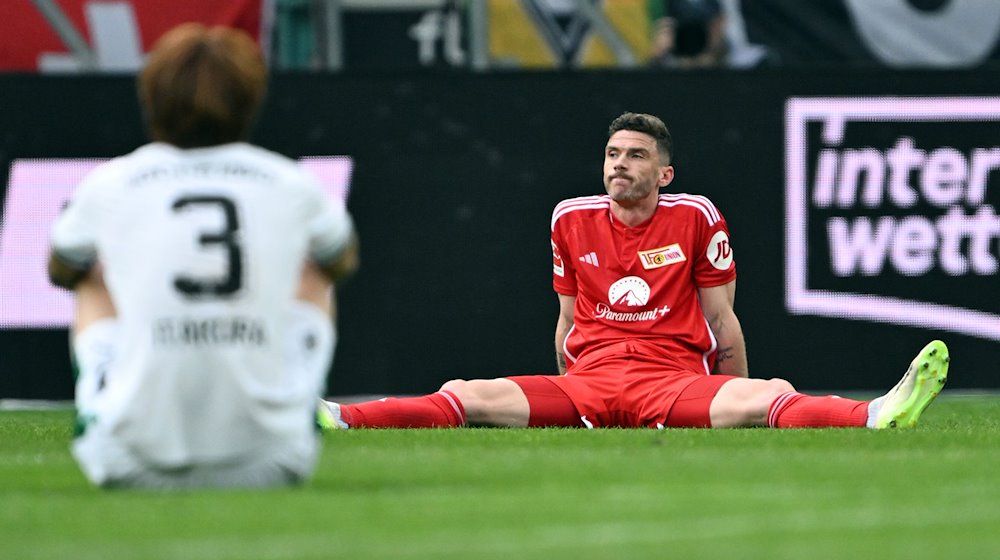 Mönchengladbachs Ko Itakura (l) und Berlins Robin Gosens (r) sitzen nach dem Spiel auf dem Platz. / Foto: Federico Gambarini/dpa