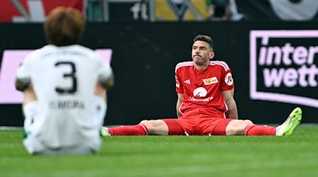 Mönchengladbachs Ko Itakura (l) und Berlins Robin Gosens (r) sitzen nach dem Spiel auf dem Platz. / Foto: Federico Gambarini/dpa