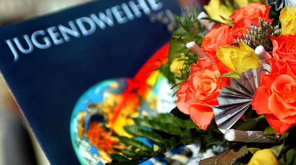 Eine Jugendweihe-Urkunde liegt in der Stadthalle in Burg neben einem Blumenstrauß. / Foto: Andreas Lander/dpa-Zentralbild/dpa